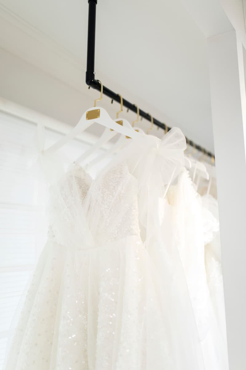 A rack of white bridal gowns in different silhouettes at a bridal boutique