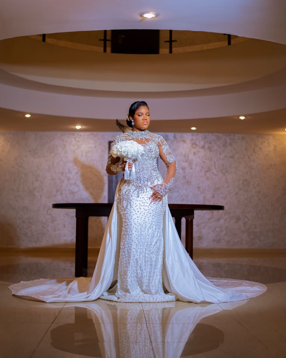 A bride in a structured, fitted sequined mermaid wedding gown with a long train, standing in a church