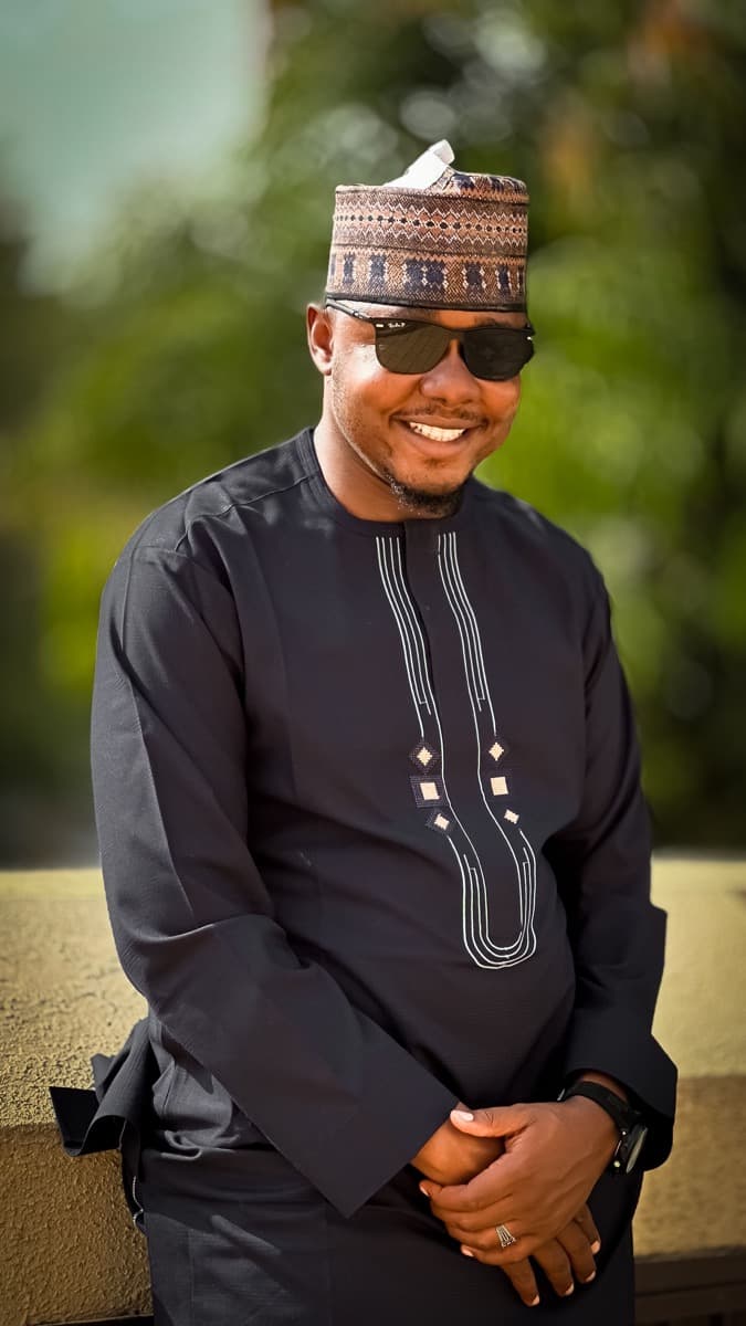 A man in a navy senator wear outfit with a mandarin collar and matching trousers