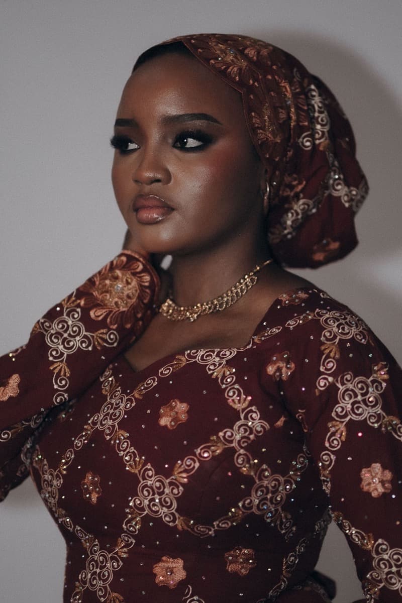 Close-up of a woman in a densely embroidered gold-and-maroon fabric with a matching headwrap